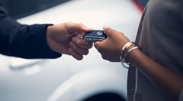 Man handing car keys to a woman near a vehicle