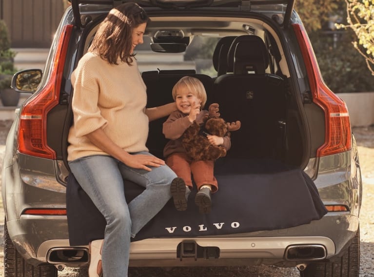 Mother and child sitting in the tailgate of a Volvo SUV