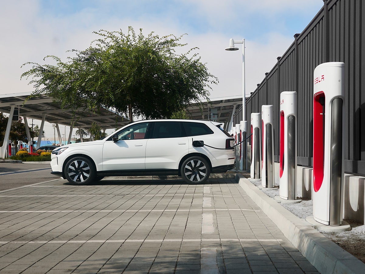Volvo EX90 charging in a lot of Tesla Superchargers