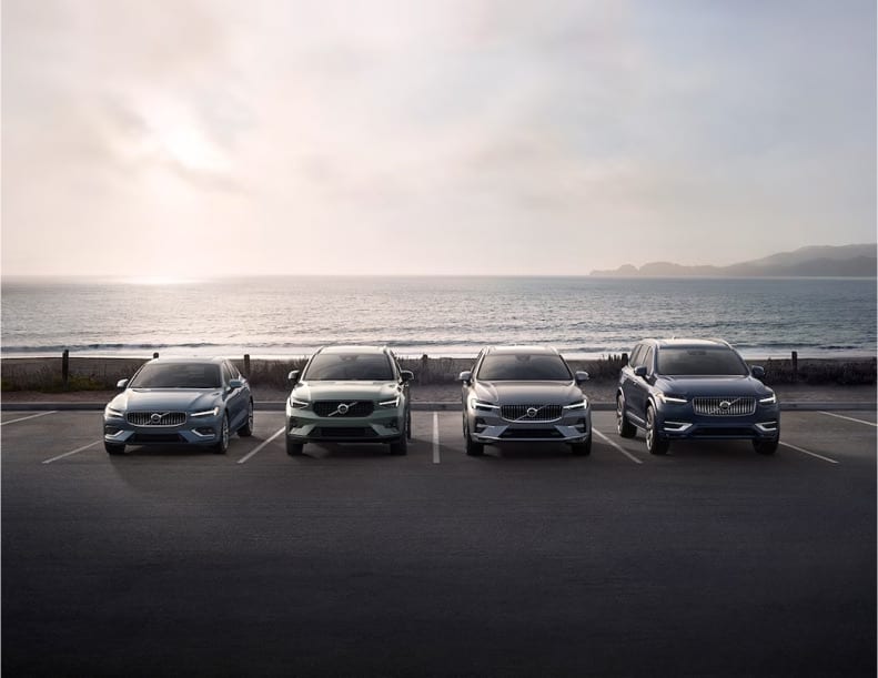 4 Volvo vehicles parked near a shoreline