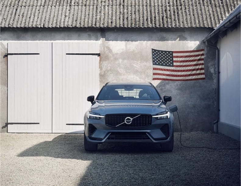 Volvo charging in front of a garage with a US Flag